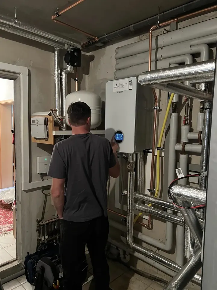 Techniker stellt die Regelung der Wärmepumpe im Heizungsraum ein