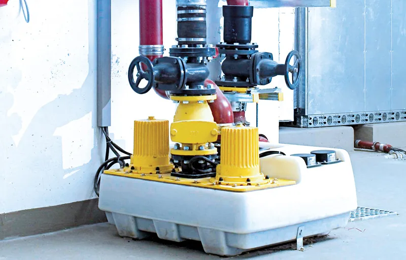 Abwasserhebeanlage mit zwei gelben Pumpen und angeschlossenen Druckleitungen